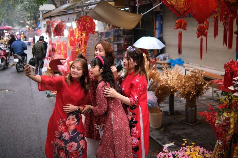 בנות לובשות שמלות וייטנאמיות מסורתיות מצטלמות במהלך טט (ראש השנה הווייטנאמי) בווייטנאם.